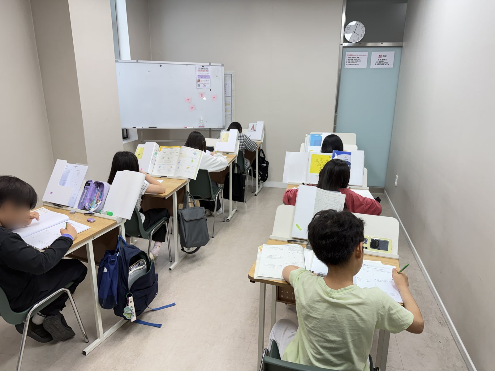 공부하는코끼리수학 초등 5~6학년 교실. 학생들이 칸막이가 있는 개인 책상에서 각자 노트에 풀이 과정을 쓰며 문제를 풀고 있다.